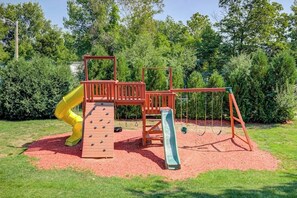 A playground with a climbing structure, slides, and swings. - Charming 2BR Lakeview 2nd-floor - Balcony - Pool (Laconia)