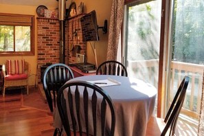 A dining area with a brick wall, a table with a tablecloth, and chairs. - 3BR Near the Beach - Deck - Tennis - Washer Dryer (Moultonborough)