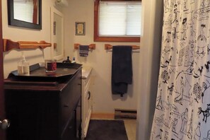 A bathroom with a wooden vanity, a towel rack, and a shower curtain with a pattern. - 3BR Near the Beach - Deck - Tennis - Washer Dryer (Moultonborough)