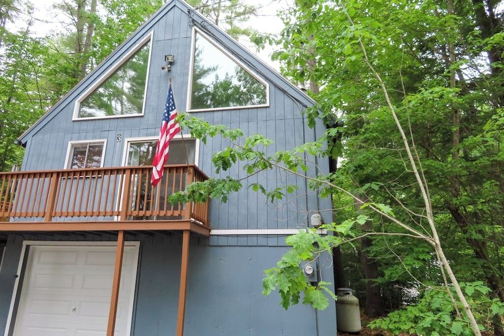 Une maison à deux étages avec un balcon, un drapeau américain et une porte de garage.
