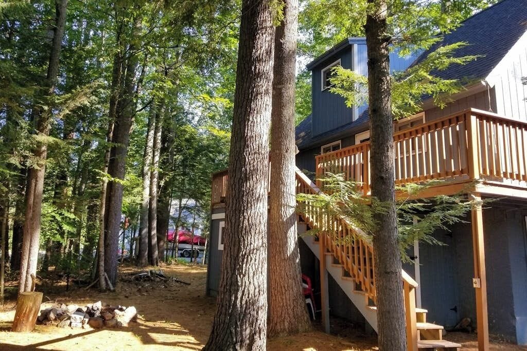 A cabin with a wooden deck and stairs leading to a covered area.