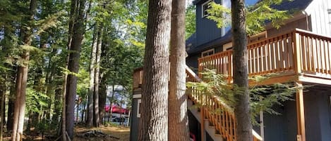 A cabin with a wooden deck and stairs leading to a covered area.