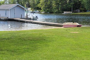 A dock with a small shed, a boat, and a grassy area by a calm lake. - 2BR Lakefront Dog Friendly - Dock - Firepit - Washer Dryer (Moultonborough)