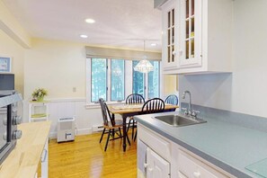 Una cocina con una mesa de comedor, sillas, un lavamanos y una ventana.