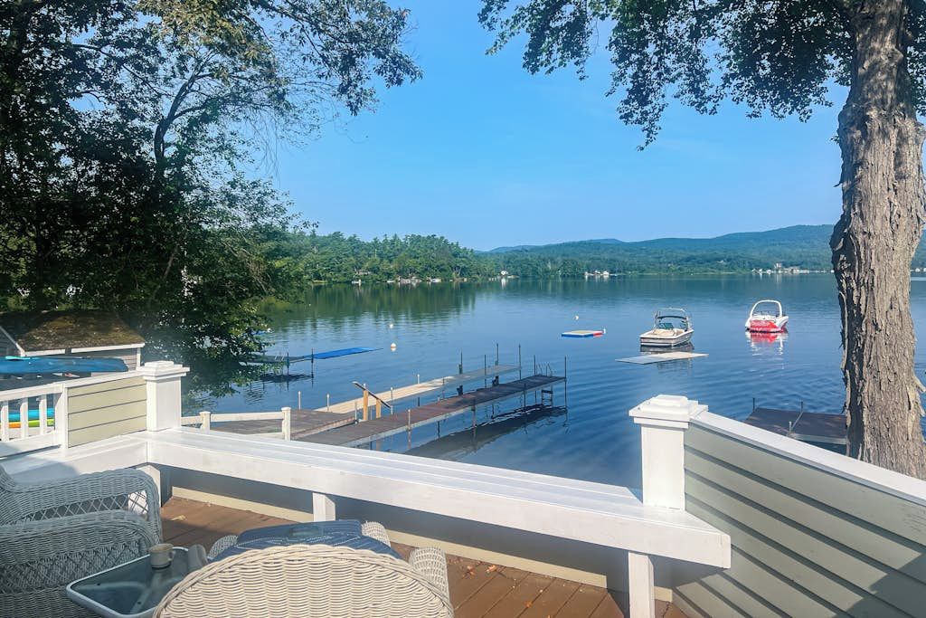 A lakeside dock with boats, a wooden deck, and a view of the lake and hills.