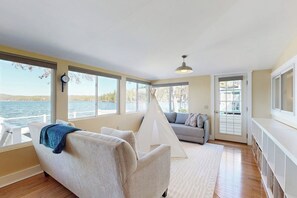 Ein Zimmer mit einer Couch, einer zeltartigen Konstruktion und Blick auf das Wasser.