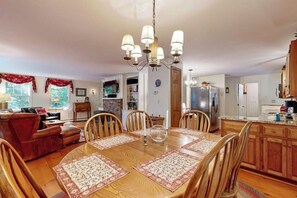 A dining area with a wooden table, chairs, and a chandelier. - Picturesque Squam Lake House: beach and dock access (Center Harbor)
