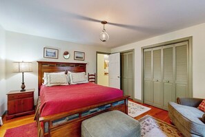 Ein Schlafzimmer mit einem hölzernen Bett, einem Nachttisch, einer Lampe, einem Sessel und einem Kleiderschrank.