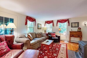 Ein Wohnzimmer mit einer Couch, einem Sessel und einem roten Teppich mit Muster.