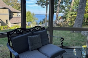 A covered outdoor seating area with a view of a body of water and surrounding greenery.
