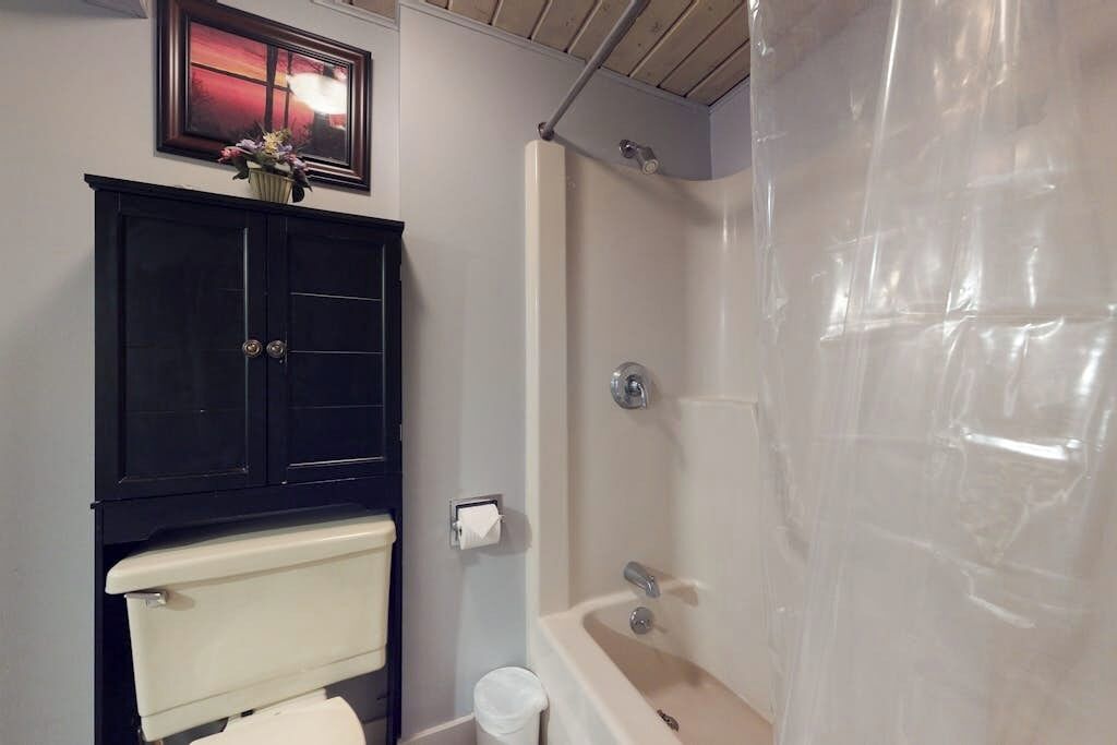 Et badeværelse med toilet, skab, brusekabine og håndklædestige.
