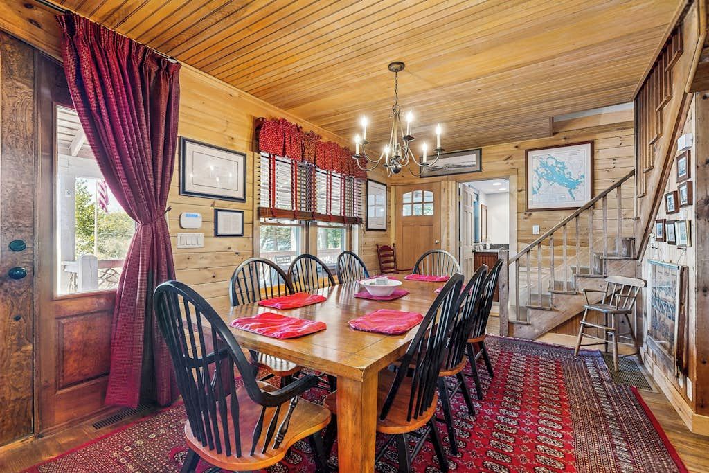 Un coin repas en bois avec une grande table, des chaises et un lustre.