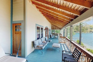 A covered porch with outdoor seating, a door, and a view of a lake. - Captivating 3BR Lakefront - Washer Dryer (Meredith)