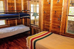 Une cabine avec des lits superposés, une lampe et des murs en bois.