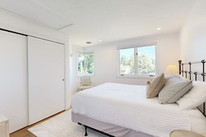 Ein Schlafzimmer mit Bett, Fenster, Nachttisch und Kleiderschrank.