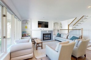 Ein modernes Wohnzimmer mit Kamin, einer Sofagarnitur, einem Couchtisch und einer Treppe.