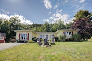 A two-story house with a front yard, a fire pit, and two Adirondack chairs. - 3BR Lakeview - Fireplace - Patio - Firepit (Gilford)