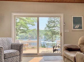 A room with a large sliding glass door leading to a deck with outdoor furniture. - 3BR lakefront home with deck, dock, & game room (Alton)