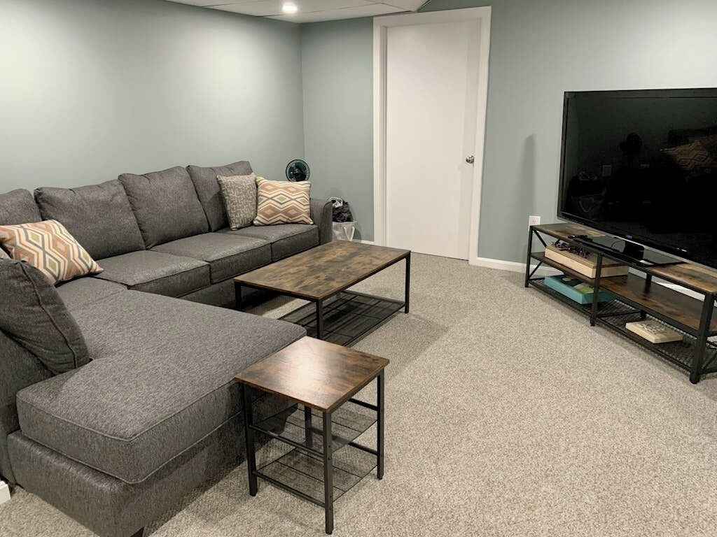 A living room with a sectional sofa, a coffee table, a TV on a stand, and a door.