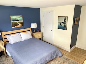A bedroom with a bed, nightstands, a lamp, and wall art. - 3BR lakefront home with deck, dock, & game room (Alton)