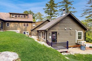 A two-story house with a front porch, a chimney, and a small deck. - 4BR Beautiful renovated home, centrally Located (Gilford)