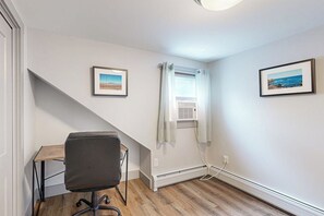 A room with a desk, a chair, a window with curtains, and two framed pictures on the wall. - 4BR Beautiful renovated home, centrally Located (Gilford)