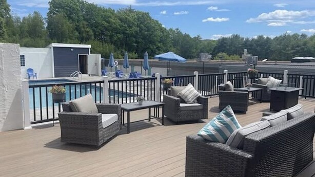 A rooftop deck with outdoor furniture, a pool, and a view of the surrounding area.