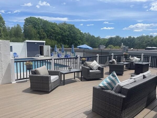 Une terrasse sur le toit, aménagée avec du mobilier d’extérieur, une piscine et offrant une vue sur les environs.