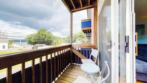 A balcony with a wooden railing, a table, and two chairs.