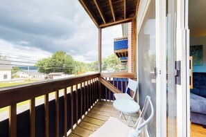 Un balcon avec une balustrade en bois, une table et deux chaises.