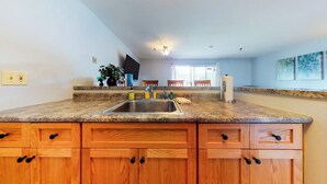 A kitchen with granite countertops, wooden cabinets, a sink, and a dining area with a table and chairs.
