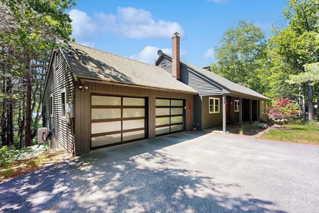 A two-story house with a garage, a chimney, and a driveway.