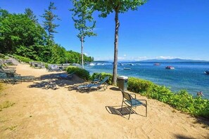 A beach with lounge chairs, a clear view of the sea, and boats in the distance. - 3BR withbeach, pool, tennis, game room, porch &views (Gilford)