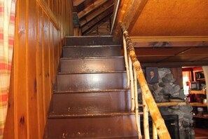 A wooden staircase with a handrail, leading to a room with a stone wall and a framed picture. - Charming 3BR Lakefront Dog Friendly (Moultonborough)