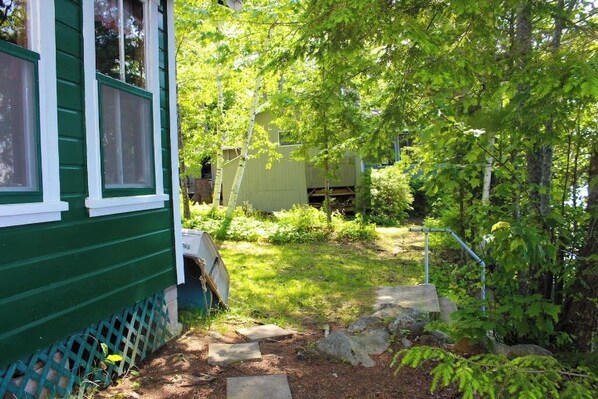 A green house with a fenced yard, a wooden deck, and a small shed. - Charming 3BR Lakefront Dog Friendly (Moultonborough)