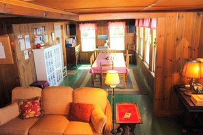 A cozy room with a sofa, a small table, a lamp, and a dining area with a table and chairs. - Charming 3BR Lakefront Dog Friendly (Moultonborough)