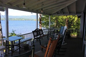 A covered outdoor seating area with tables and chairs, overlooking a body of water. - Charming 3BR Lakefront Dog Friendly (Moultonborough)