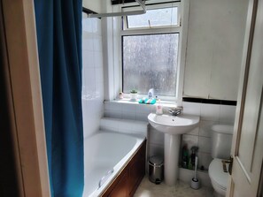 Une salle de bain avec une baignoire, un lavabo, des toilettes et une fenêtre.