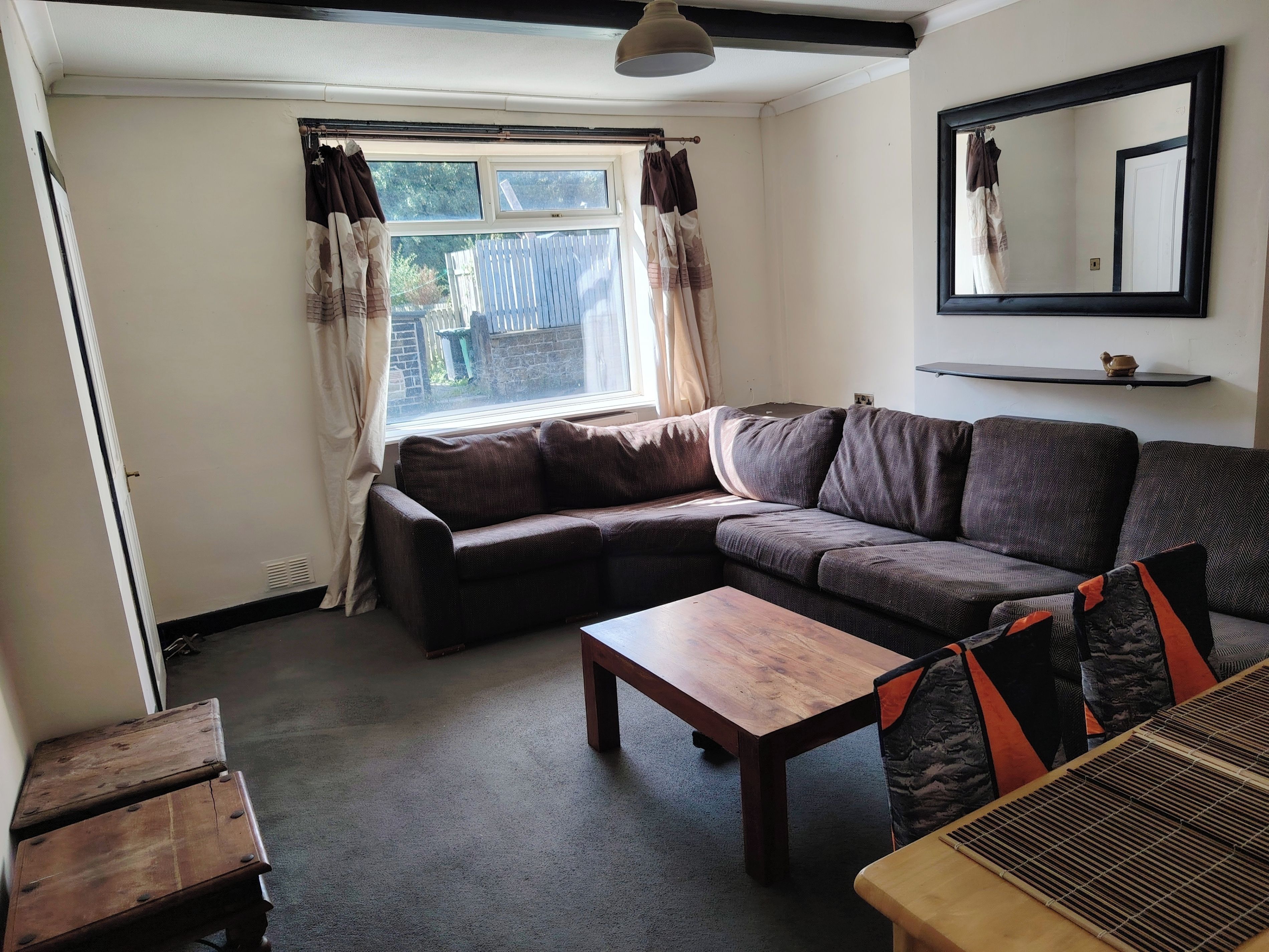 A living room with a sofa, a wooden coffee table, and a window with curtains.
