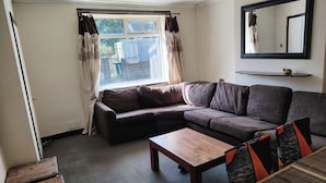 Uma sala de estar com sofá, mesa de centro de madeira e janela com cortinas.