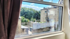 Una ventana con vista a un edificio de ladrillo, una valla de madera y follaje.