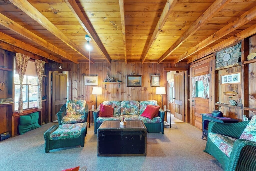 A cozy room with wooden walls and ceiling, a sofa set, a coffee table, and a fireplace.