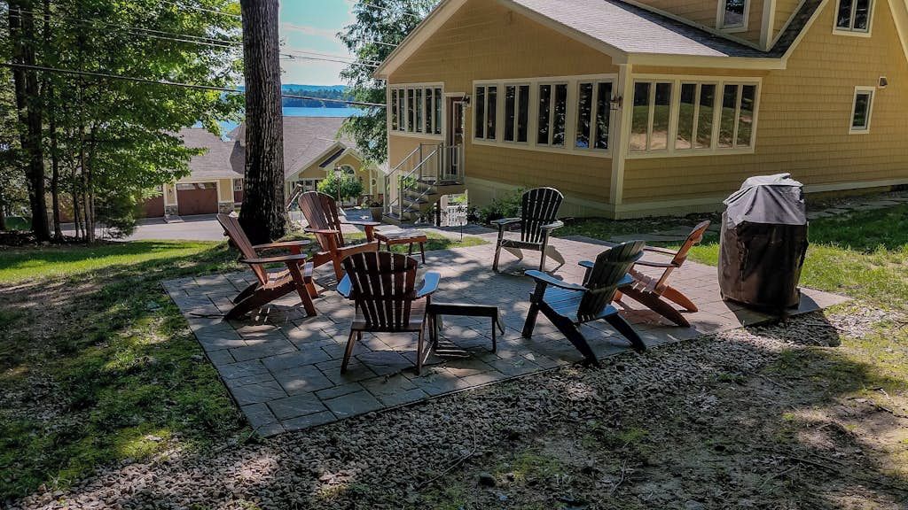 A patio with outdoor furniture and a grill, overlooking a body of water.