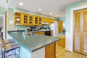 A kitchen with wooden cabinets, a countertop, and a refrigerator. - Stunning 2BR Lakefront - Dock - Patio - Washer Dryer (Moultonborough)