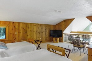 Une chambre avec deux lits, une télévision et un balcon équipé de chaises.