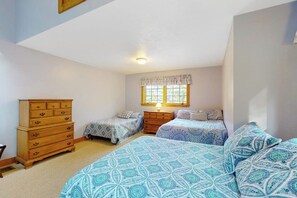 Ein Schlafzimmer mit zwei Betten, einem Schminktisch und einem Fenster mit Vorhängen.