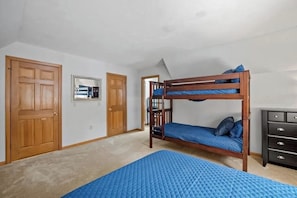 A bedroom with a bunk bed, a dresser, and a door. - 3BR home near outdoor rec with deck & games (Gilford)