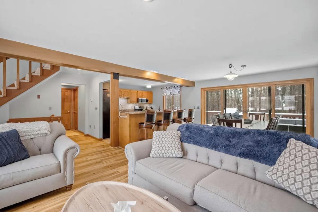 A spacious living area with a sofa, a coffee table, and a staircase leading to an upper level.
