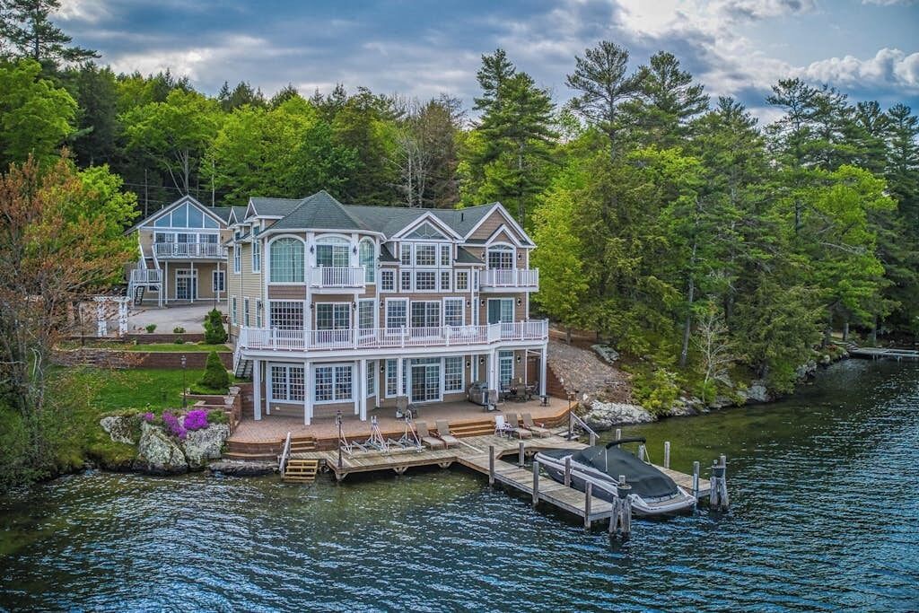 A large, multi-story waterfront property with a dock and a boat.