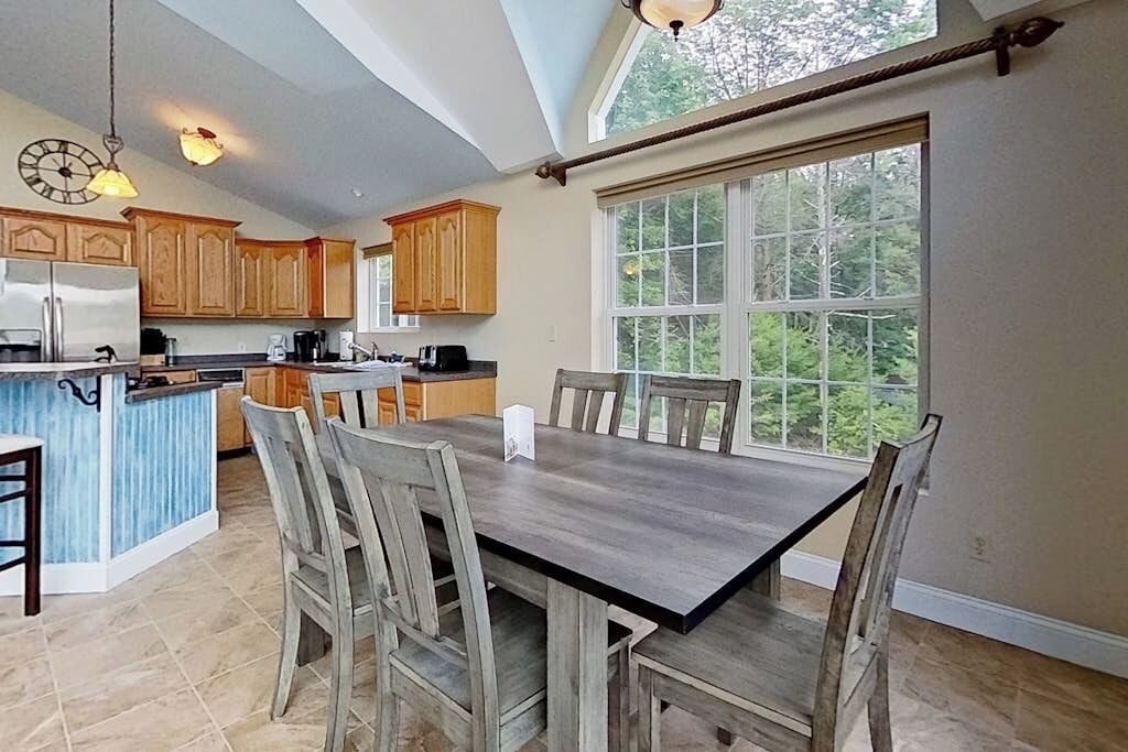 A kitchen with wooden cabinets, a central island, and a dining table with chairs.